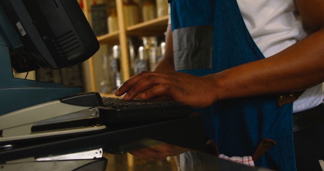 Barista Working on Cafe Computer Wearing Blue Apron - Free Images, Stock Photos and Pictures on Pikwizard.com