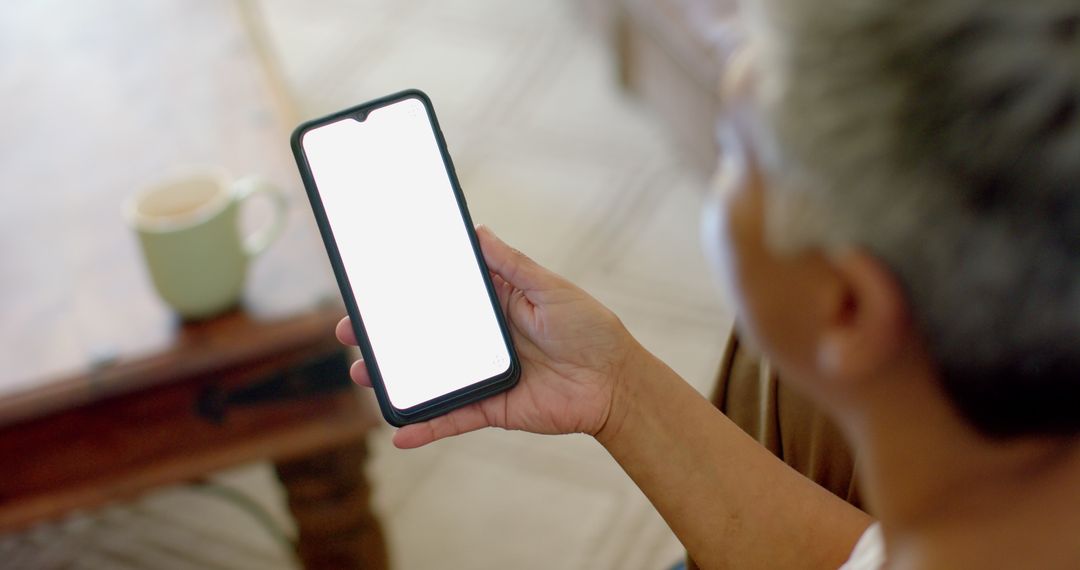 Senior Woman Using Smartphone at Home With Blank Screen for Copy Space