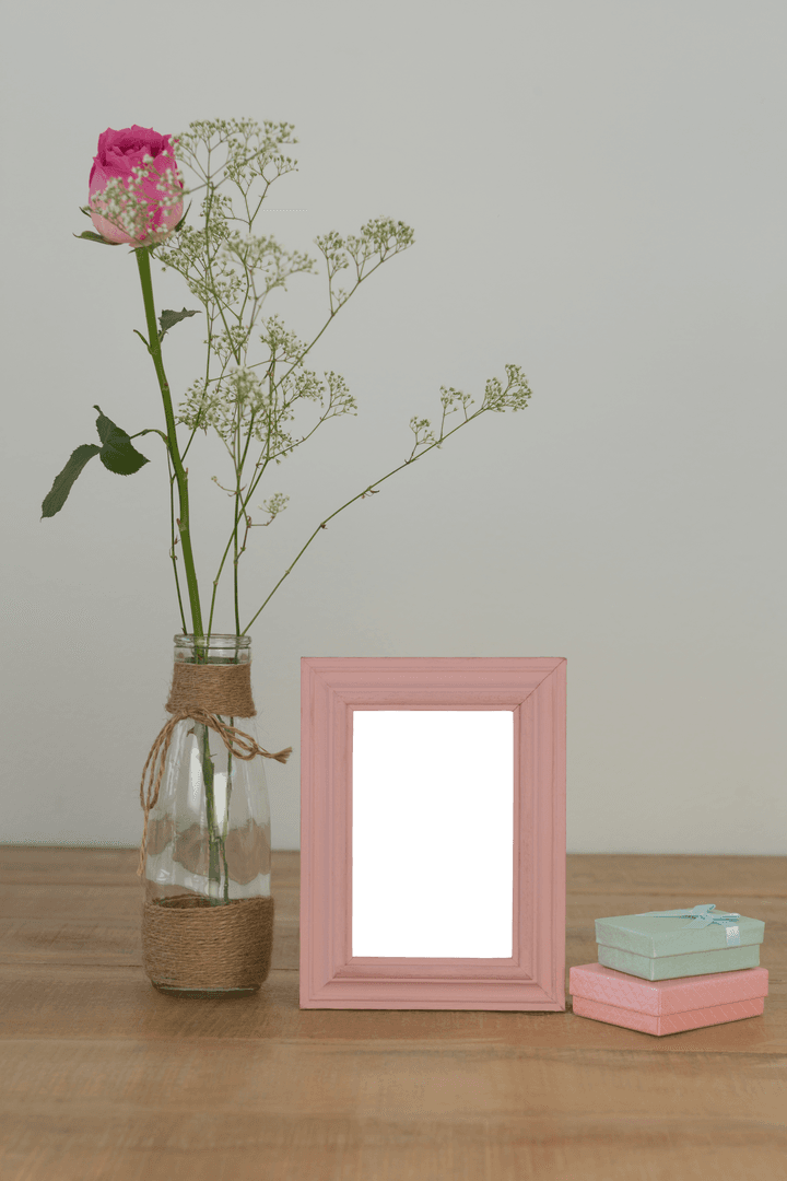 Transparent Rose Vase and Empty Pink Photo Frame on Wooden Table