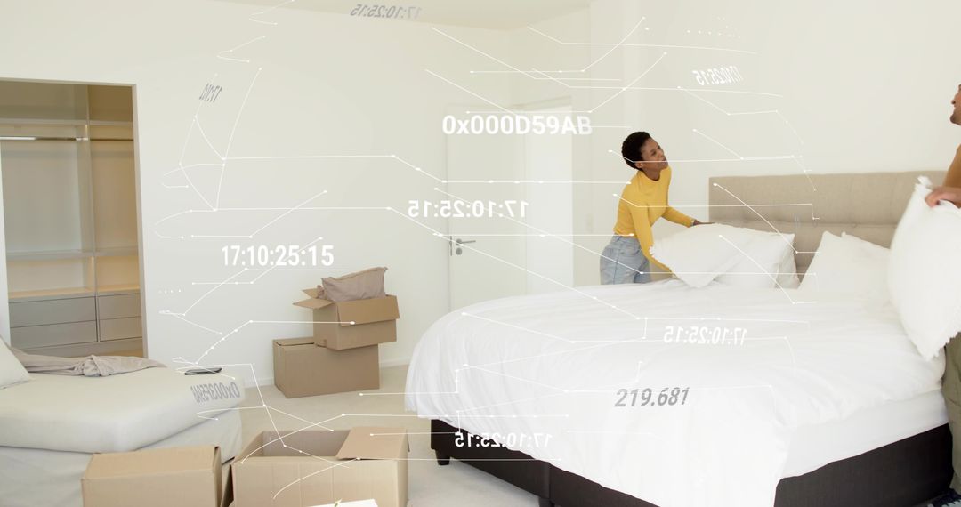 Couple Making Bed While Unpacking in Minimalist Bedroom with White Linens and Moving Boxes