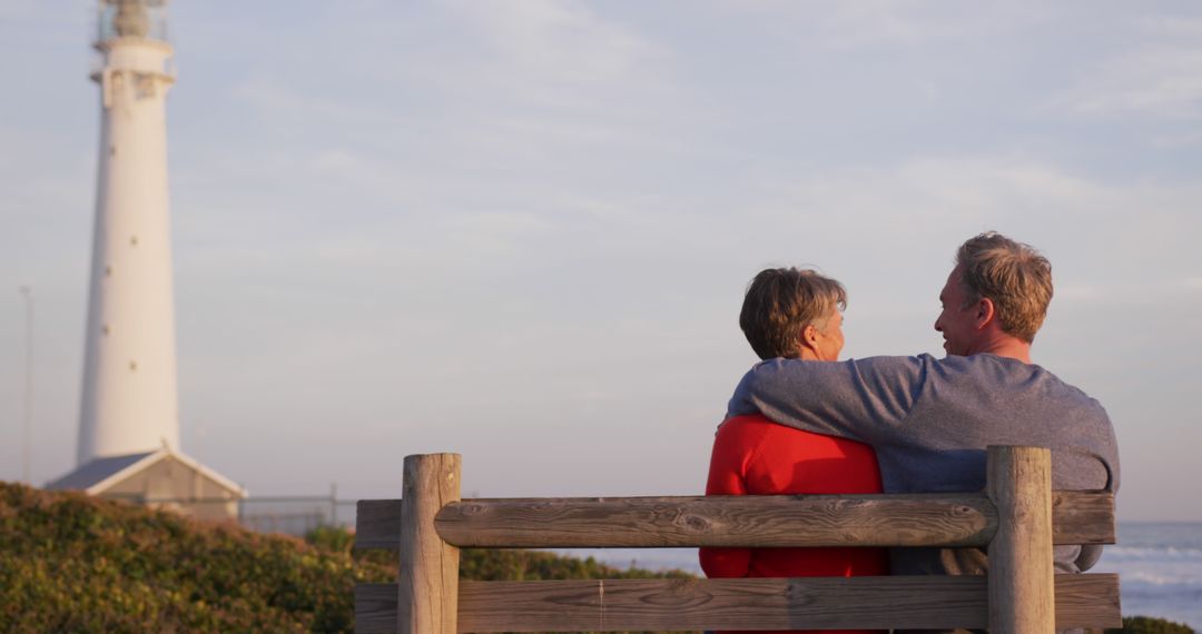 Senior Couple Enjoying Sunset on Beach Bench Near Lighthouse - Free Images, Stock Photos and Pictures on Pikwizard.com