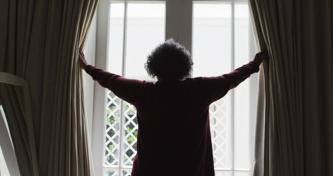 Rear view of senior african american woman opening curtains of the window at home - Free Images, Stock Photos and Pictures on Pikwizard.com