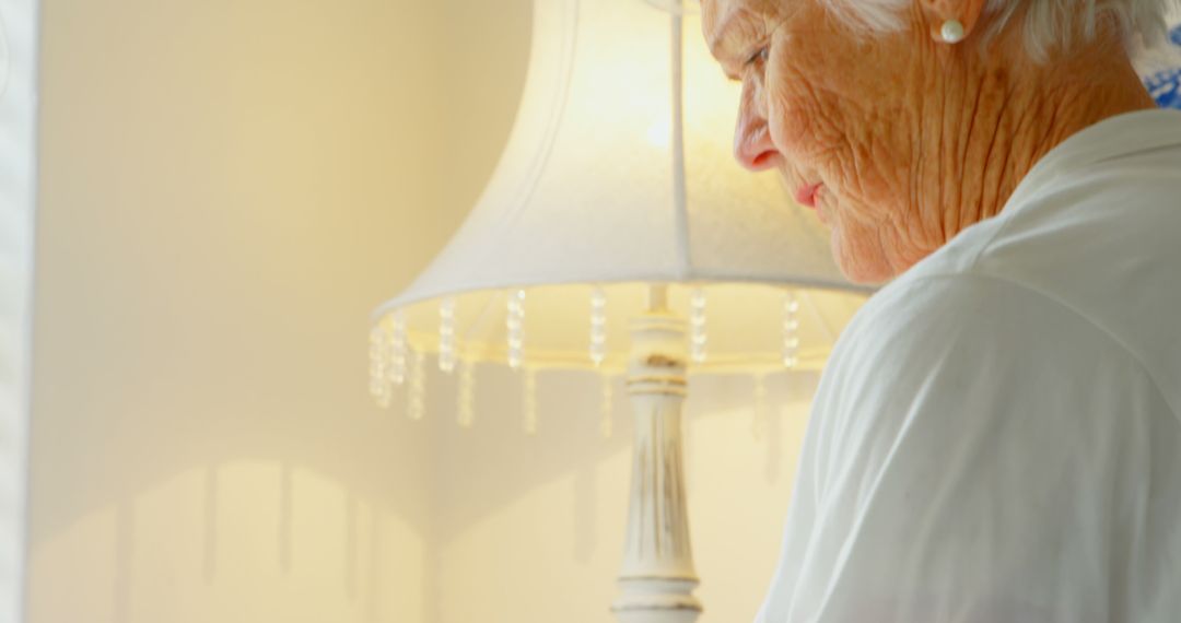 Senior Woman Enjoying Peaceful Moment Near Lamp at Home - Free Images, Stock Photos and Pictures on Pikwizard.com