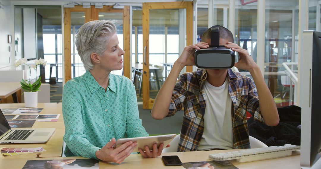 Senior Woman and Young Man Using Virtual Reality and Tablet in Modern Office - Free Images, Stock Photos and Pictures on Pikwizard.com