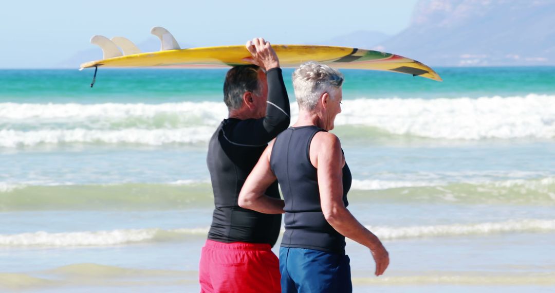 Senior Couple Carrying Surfboard on Sunny Beach - Free Images, Stock Photos and Pictures on Pikwizard.com