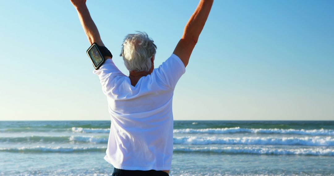 Senior man celebrating on beach with fitness tracker - Free Images, Stock Photos and Pictures on Pikwizard.com