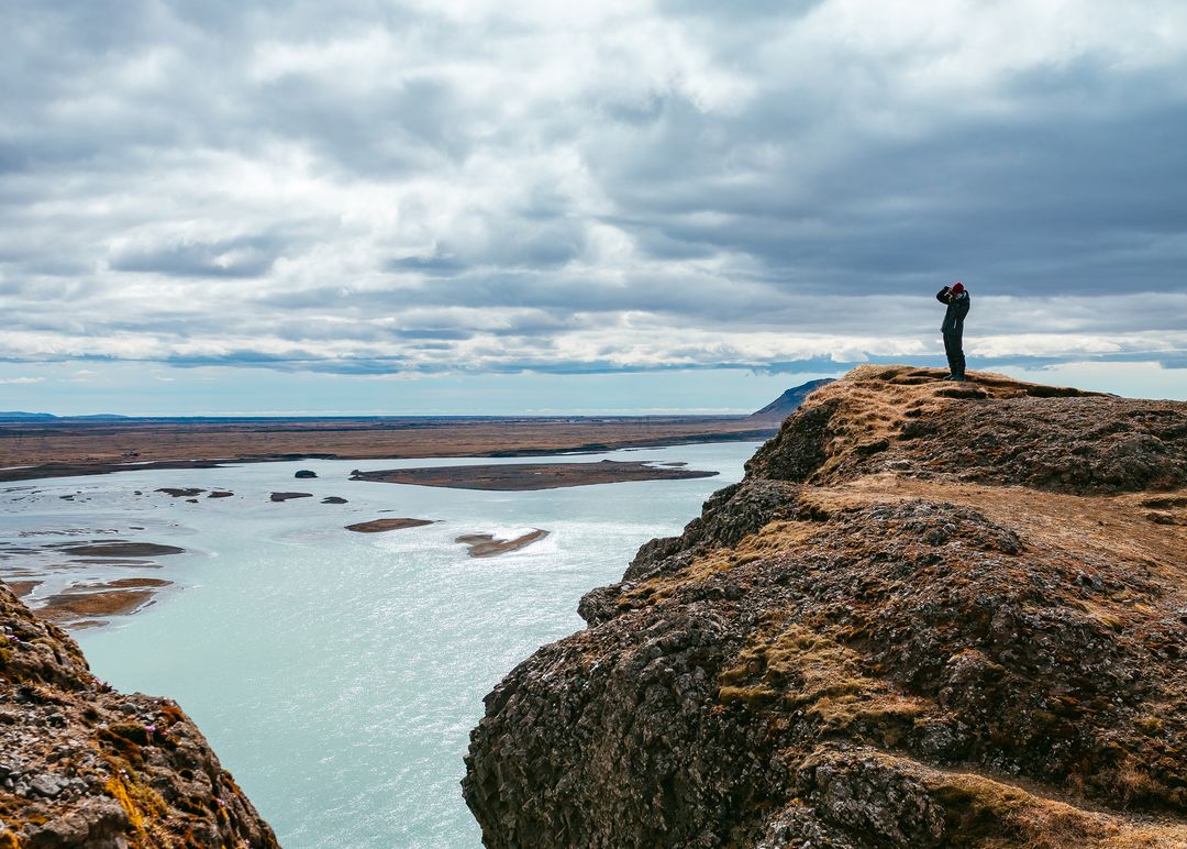 Hiker Capturing Majestic River Views from Cliff Top