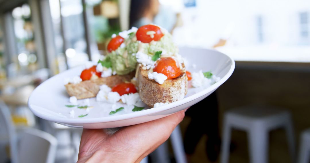 Hand Holding Plate of Avocado Toast with Cherry Tomatoes and Feta Cheese - Free Images, Stock Photos and Pictures on Pikwizard.com