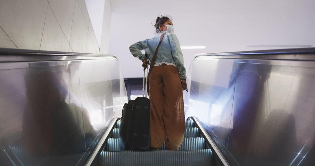 Rear View of Woman on Escalator with Luggage at Airport Terminal - Free Images, Stock Photos and Pictures on Pikwizard.com