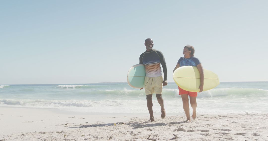 Happy Senior Couple Walking with Surfboards on Sunny Beach - Free Images, Stock Photos and Pictures on Pikwizard.com