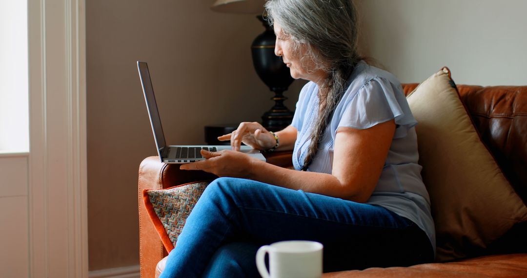 Elderly Woman Using Laptop While Relaxing on Couch - Free Images, Stock Photos and Pictures on Pikwizard.com