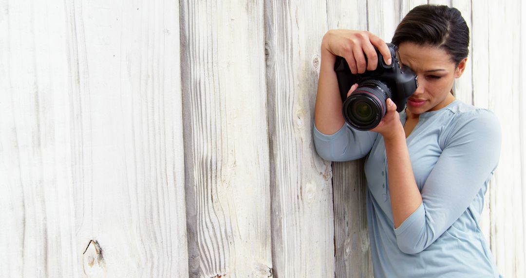 Photographer Capturing Moments with DSLR Camera Against Wooden Wall - Free Images, Stock Photos and Pictures on Pikwizard.com