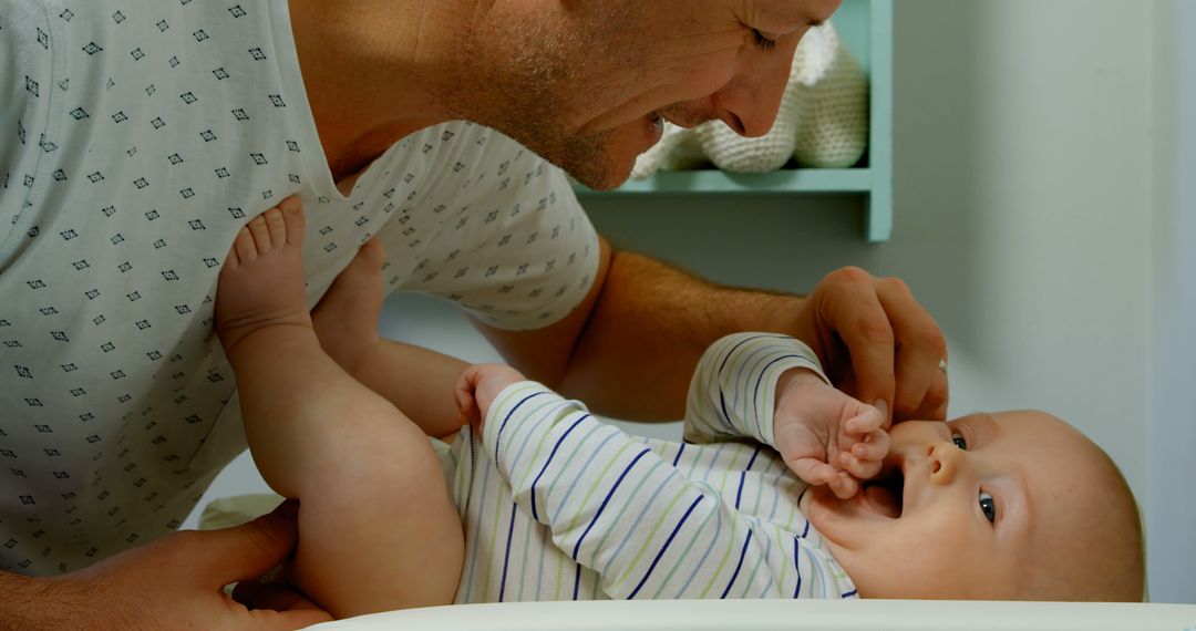 Father Smiling While Changing Baby's Diaper on Changing Table - Free Images, Stock Photos and Pictures on Pikwizard.com