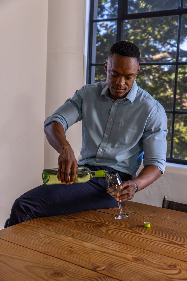 Man Pouring Wine Focused on Elegance and Leisure in Bright Rustic Room