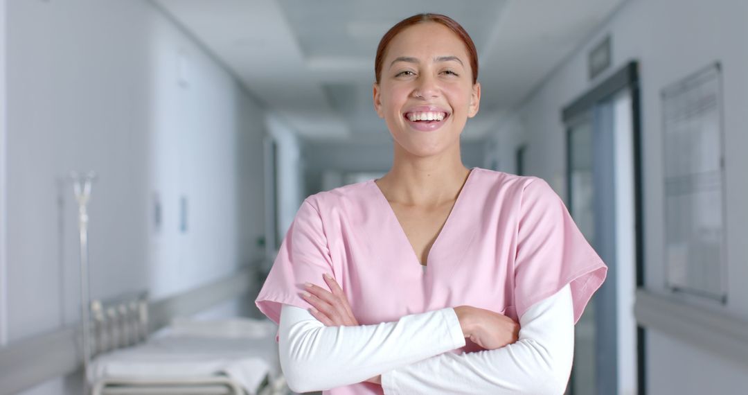 Smiling Healthcare Professional in Pink Scrubs in Hospital Hallway - Free Images, Stock Photos and Pictures on Pikwizard.com