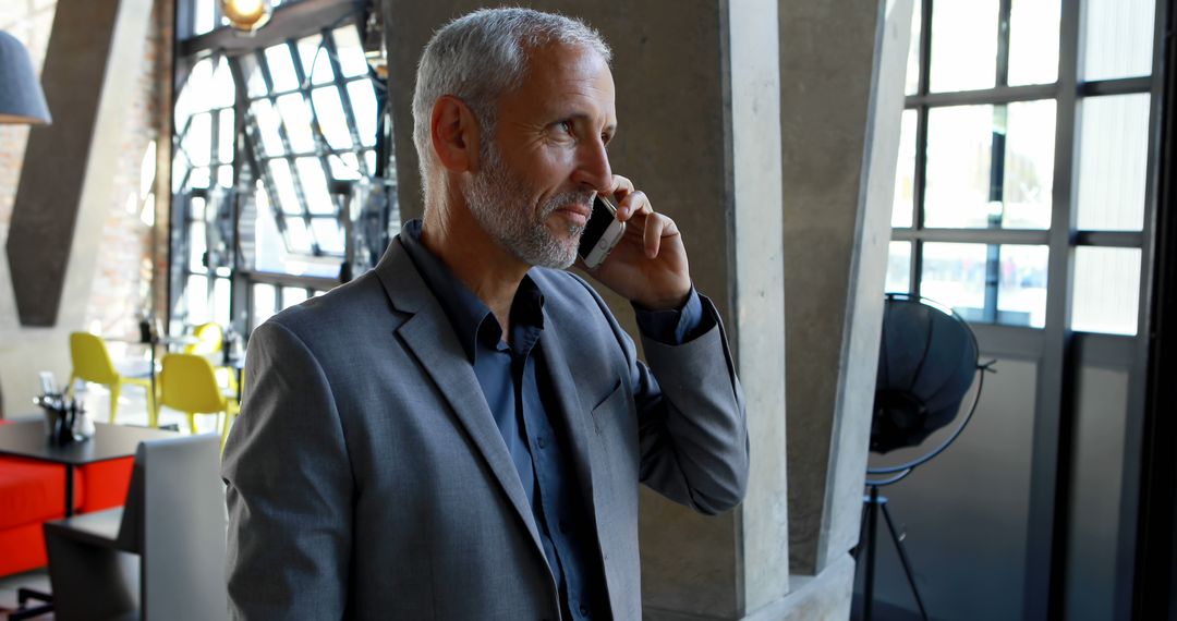 Businessman with Grey Hair Talking on Phone in Modern Office - Free Images, Stock Photos and Pictures on Pikwizard.com