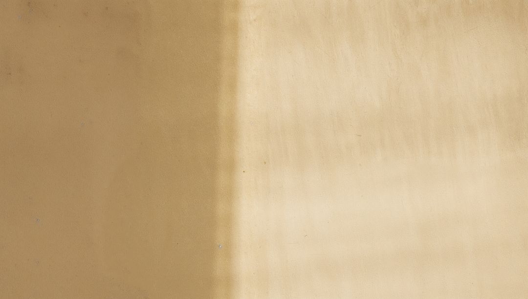 Displaying vertical light band crossing textured beige wall with patina and streaks