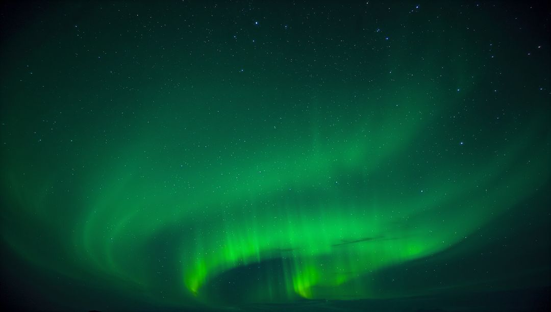 Dancing green aurora borealis curtains over starry northern sky with silhouetted horizon