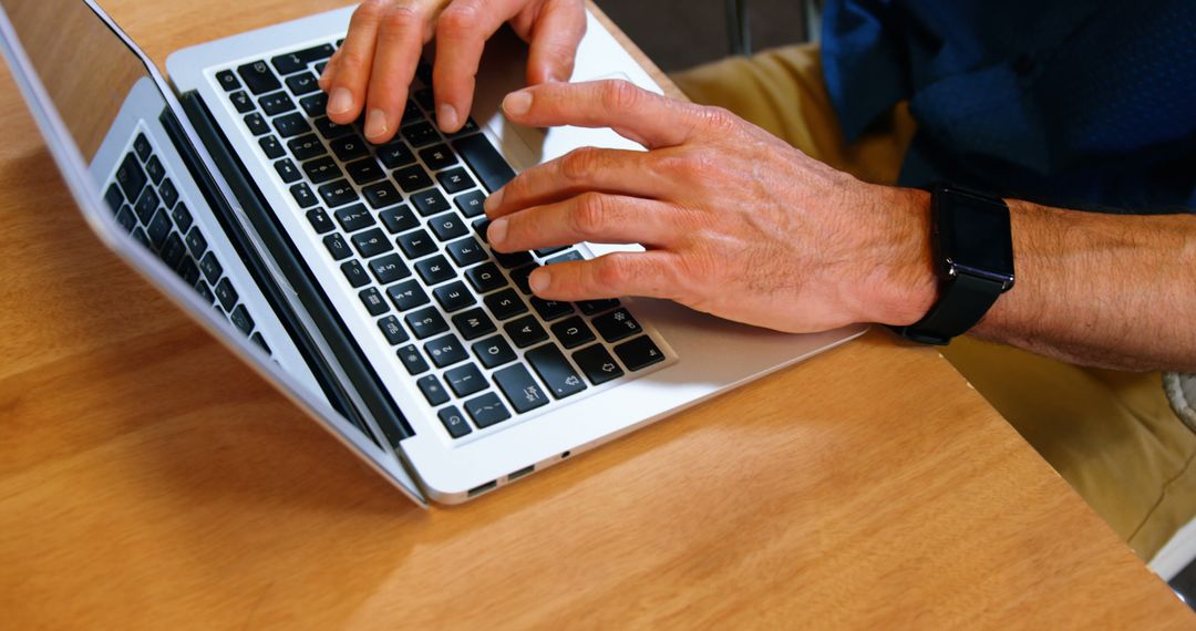 Businessman Typing on Laptop in Office on Wooden Desk