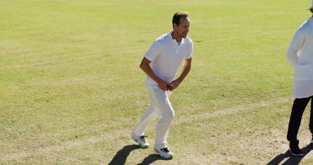 Cricketer Running to Bowl on Green Pitch in Uniform