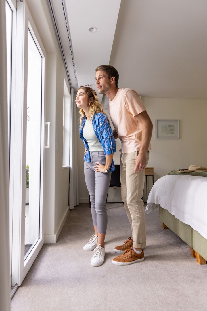 Couple Gazing Through Bedroom Window in Modern Home