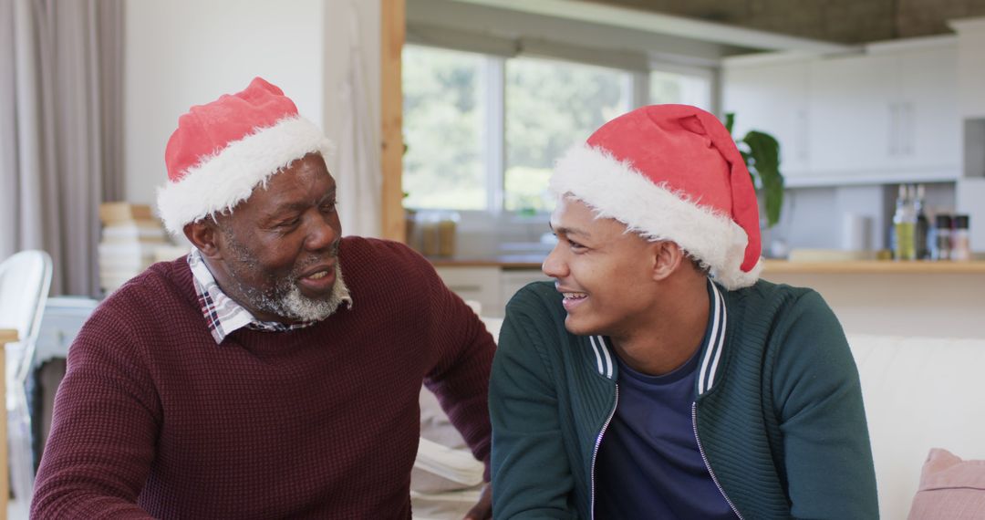 Elderly Man and Young Man Wearing Santa Hats Celebrating Christmas at Home - Free Images, Stock Photos and Pictures on Pikwizard.com