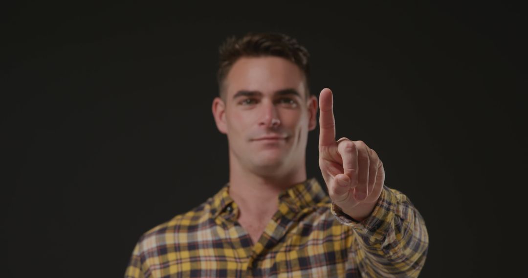 Man pointing with index finger in checkered shirt against black background - Free Images, Stock Photos and Pictures on Pikwizard.com