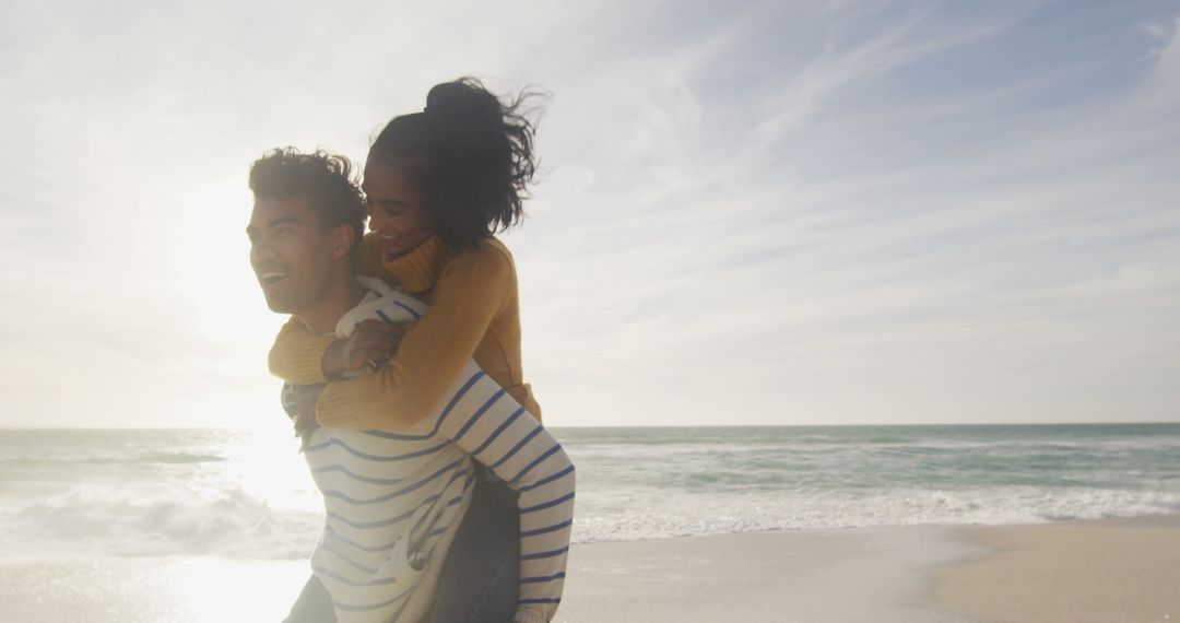 Joyful Couple Piggyback on Sandy Beach at Sunset
