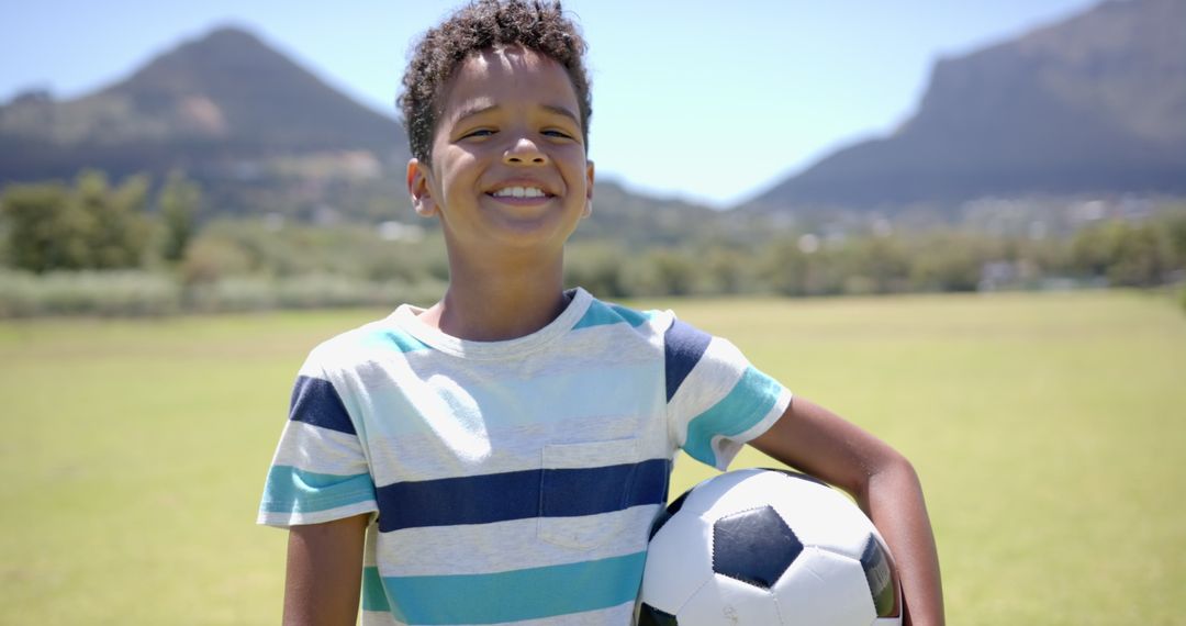 Smiling Boy with Soccer Ball in Sunlit Park