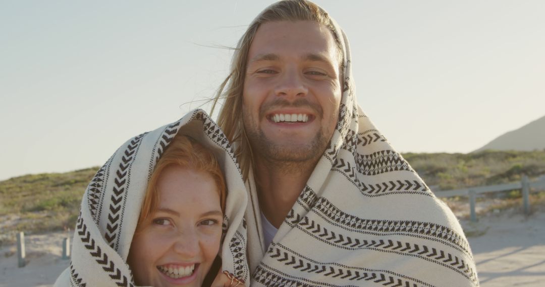 Happy Couple Smiling Wrapped in Blanket on Beach - Free Images, Stock Photos and Pictures on Pikwizard.com