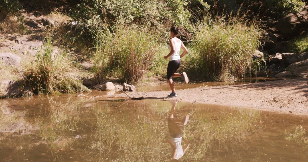 Woman running outdoors by creek in nature - Free Images, Stock Photos and Pictures on Pikwizard.com