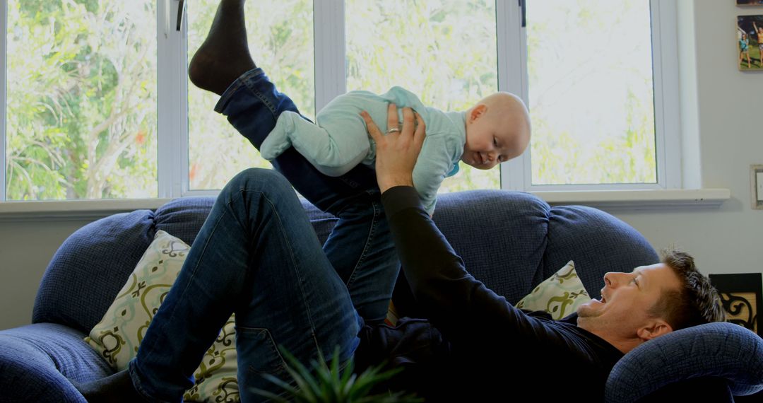 Father Playing and Lifting Baby in Cozy Living Room - Free Images, Stock Photos and Pictures on Pikwizard.com