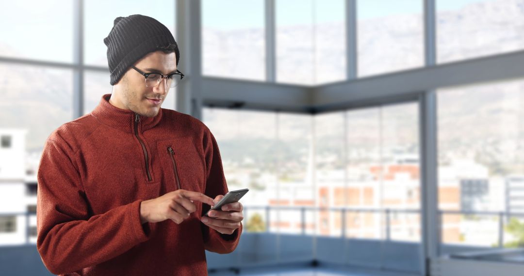 Man in Beanie Using Smartphone in Contemporary Office Space