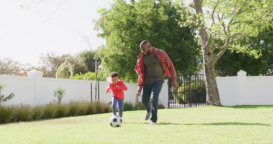 Happy african american father and his son playing football in garden - Free Images, Stock Photos and Pictures on Pikwizard.com