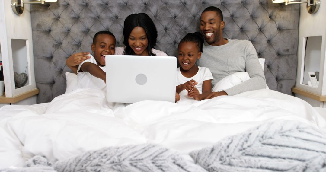 Happy African American Family Enjoying Time Together on Bed with Laptop - Free Images, Stock Photos and Pictures on Pikwizard.com