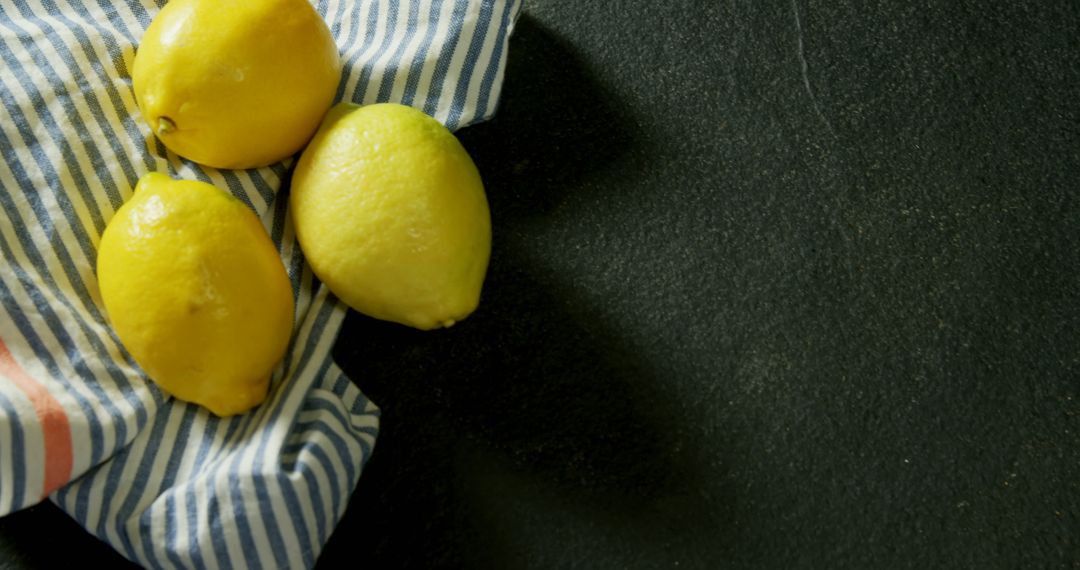 Fresh Lemons on Striped Cloth Against Dark Slate Background - Free Images, Stock Photos and Pictures on Pikwizard.com