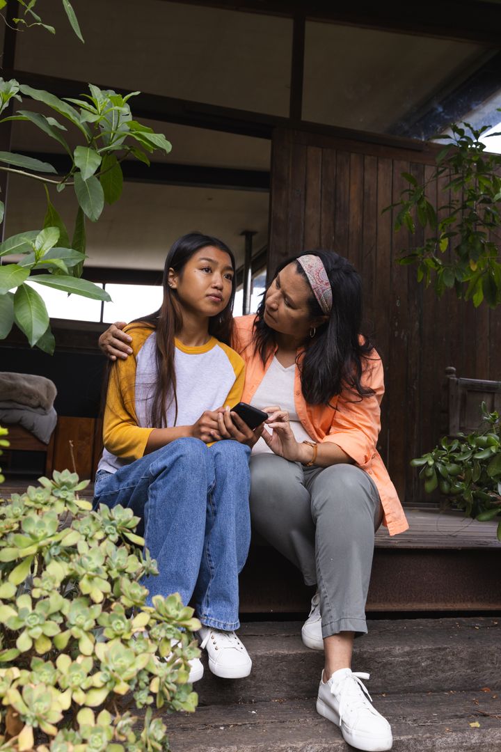 Mother and Daughter Connecting on Porch with Smartphone in Rustic Setting