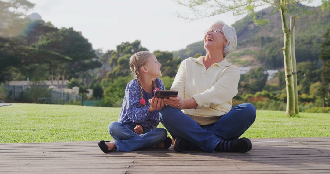 Grandmother Bonding with Granddaughter Using Digital Tablet in Outdoor Park - Free Images, Stock Photos and Pictures on Pikwizard.com