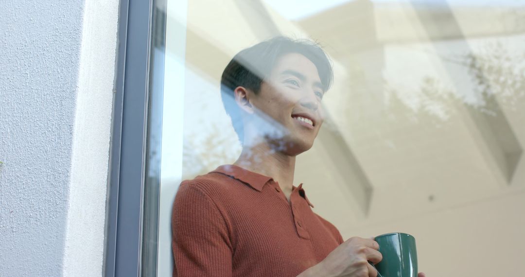 Man Looking Out Window with Mug in Airy Modern Space