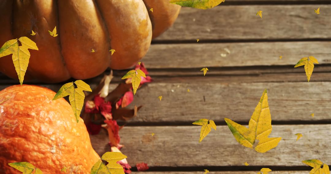 Autumn Pumpkins with Falling Leaves on Wooden Surface