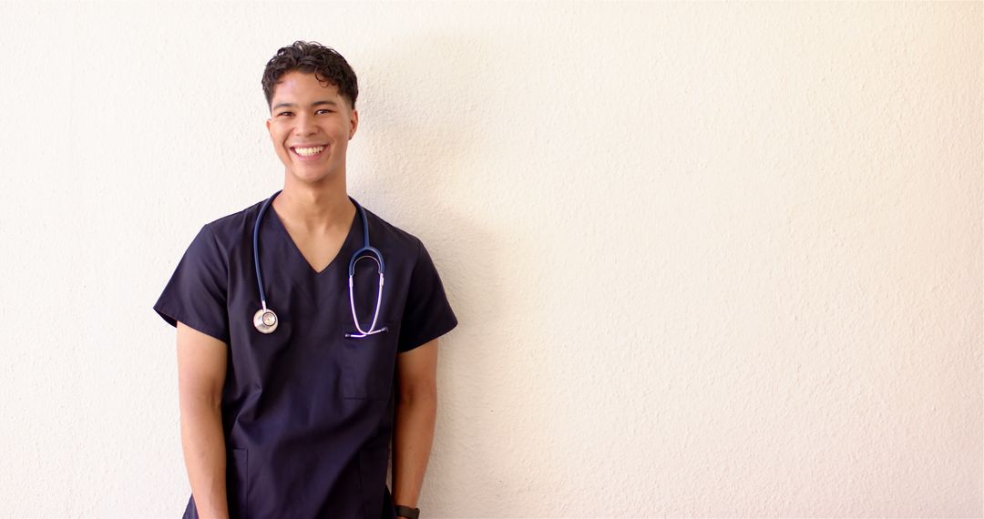 Smiling Male Nurse in Scrubs with Stethoscope Against Plain Background