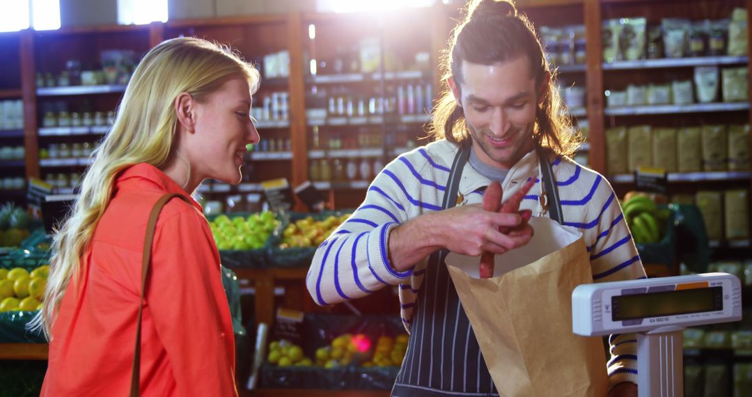 Smiling male cashier with long hair helps female customer at organic grocery store - Free Images, Stock Photos and Pictures on Pikwizard.com