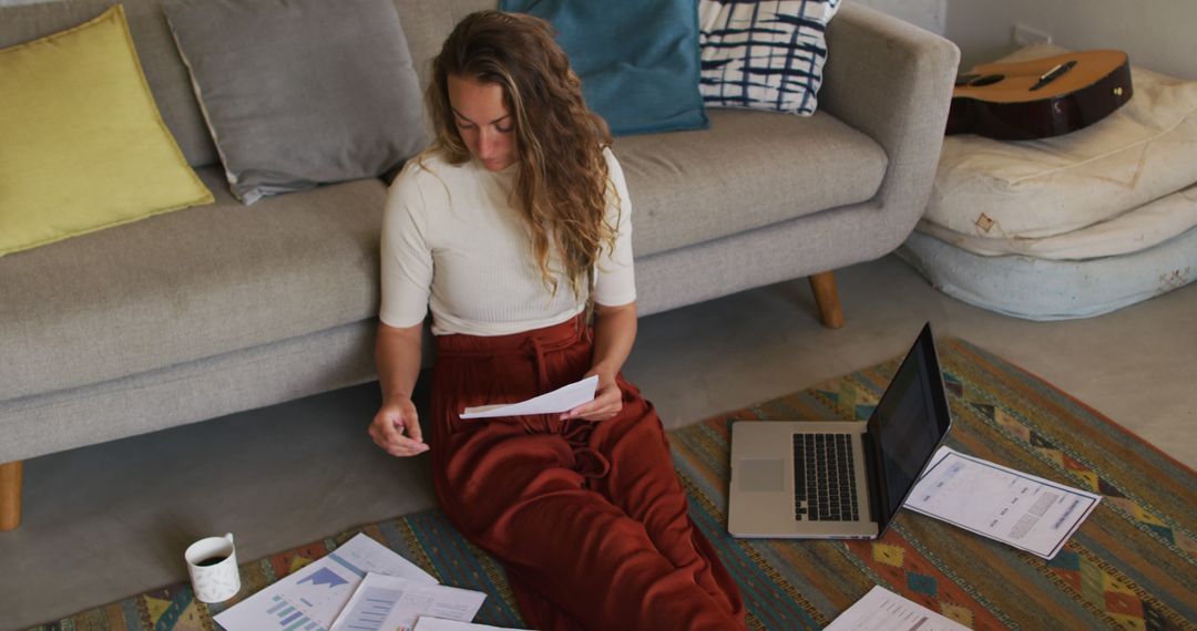 Young Woman Analyzing Financial Reports Sitting on Floor in Cozy Living Room - Free Images, Stock Photos and Pictures on Pikwizard.com