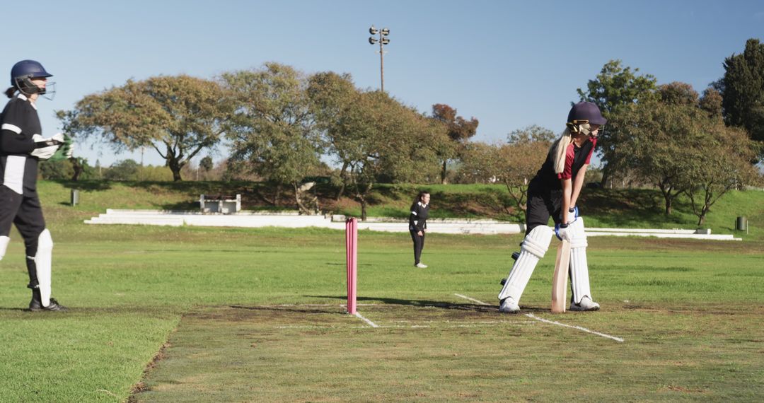 Female Cricketers in Action on Lush Green Field with Pink Stumps