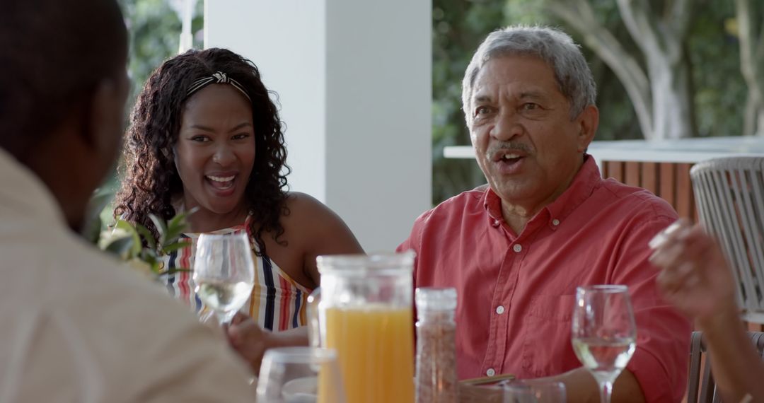 Multi-generational family enjoying lively outdoor brunch on patio with juice and laughter
