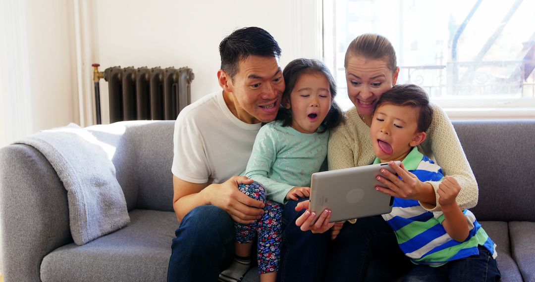 Excited Family Using Tablet Together on Couch in Bright Living Room - Free Images, Stock Photos and Pictures on Pikwizard.com