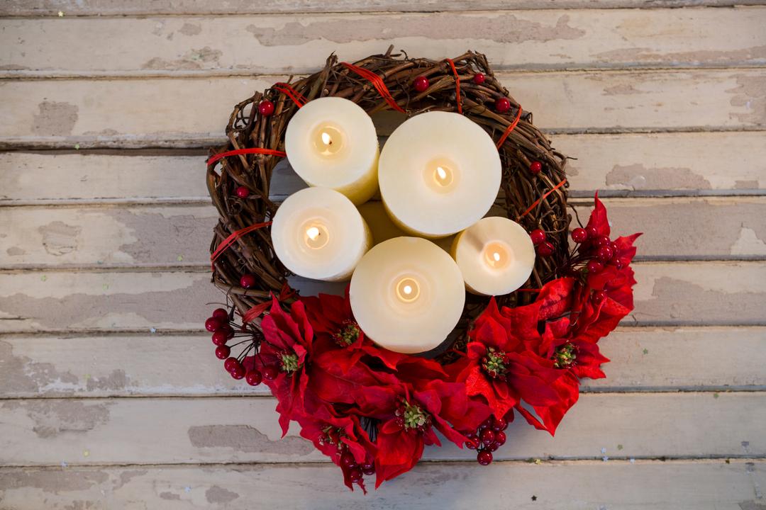 Christmas Candles in Wreath with Red Flowers on Wooden Plank - Free Images, Stock Photos and Pictures on Pikwizard.com
