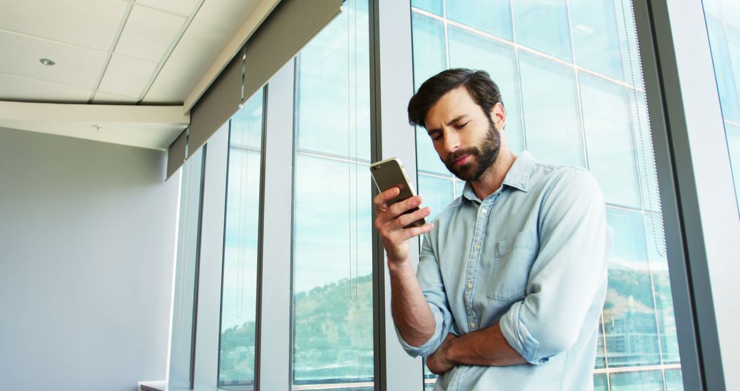 Businessman Contemplating Message on Smartphone in Modern Office - Free Images, Stock Photos and Pictures on Pikwizard.com