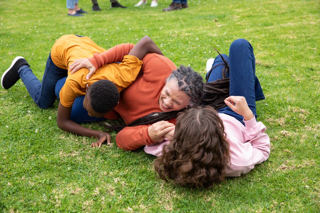 Diverse Family Playing on Green Grass in Park Enjoying Sunshine and Laughter