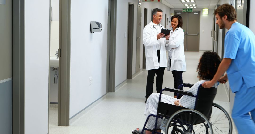 Doctors Consulting in Hospital Corridor with Nurse Pushing Wheelchair - Free Images, Stock Photos and Pictures on Pikwizard.com